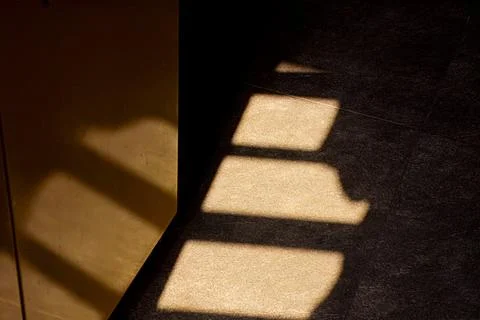 Shadows from a window falling on a dark tiled floor Stock Photos