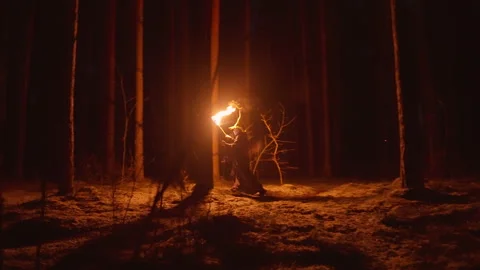 In a shadowy forest, a wizard carries a torch as he makes his way through the Stock Footage 306328244