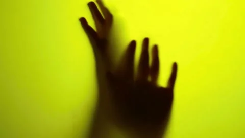 Shadowy hands moving behind translucent glass on yellow background footage Stock-Footage 342905983