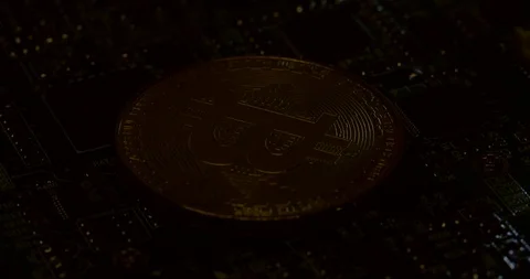Shadowy rotating shot of a bitcoin on an electronic circuit board Stock Footage 92525388