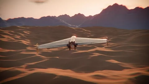Shahed kamikaze drone soaring over desert dunes at sunset with mountains Video stock 331493735
