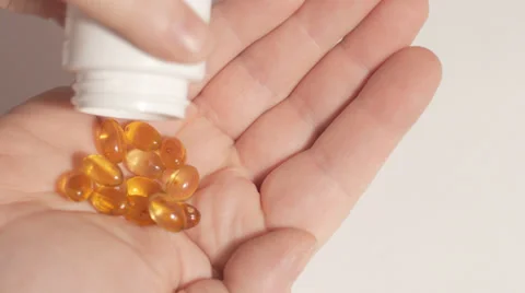 Shaking cod liver oil capsules into hand Stock Footage 33910354