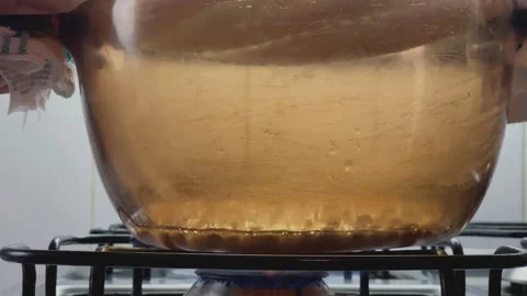 Shaking the popcorn pan. First popping popcorn.Hot glass pan. Stock Footage 148190175