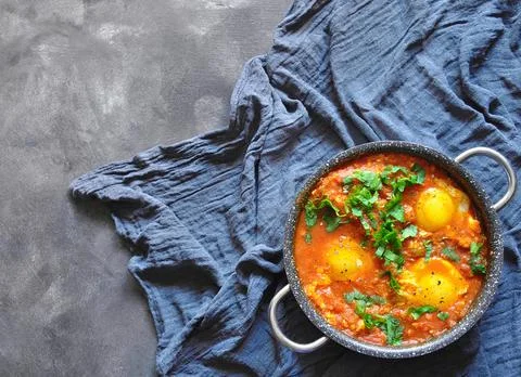 Shakshuka in pan on a gray rustic background.Middle eastern traditional dishe Stock Photos