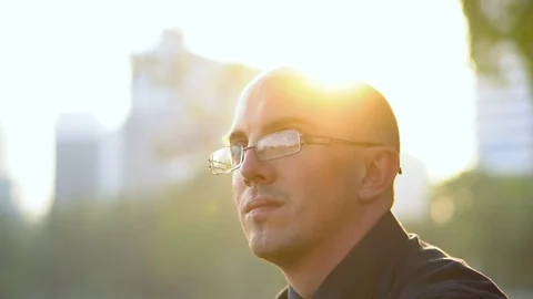 Shaky Handheld Slowmo Side View Portrait Of Late 20s Glasses Man Sitting in Park Stock Footage 102359200