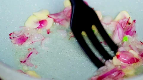 Shallots and garlic being sautéed in butter on a pan Stock Footage 329830513