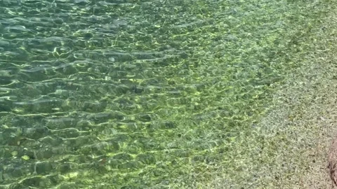 Shallow clear water waves over brown pebble sand shore viewed from above Stock Footage 243441897