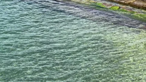 Shallow clear water waves over brown pebble sand shore viewed from above Stock Footage 243441955