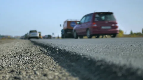 Shallow depth of field. Close-up of a freshly paved asphalt road. Cars pass on Stock-Footage 140212653
