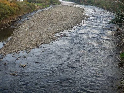 A shallow fast river. Stream with shallows. Fast river in the city. Stock Photos
