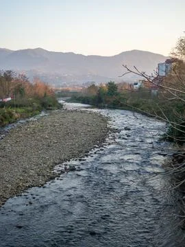A shallow fast river. Stream with shallows. Fast river in the city. Concret.. Stock Photos