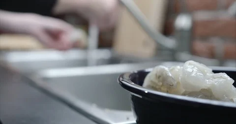 Shallow focus bowl of shrimp while woman peels more Stock Footage 98196170