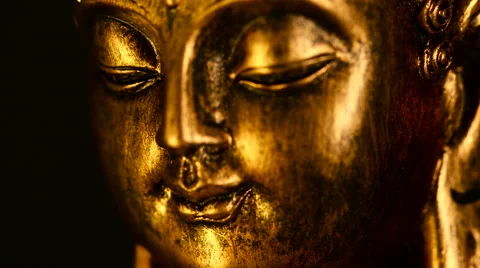Shallow focus closeup of rotating face of a golden Buddha figure against black Stock Footage 65791442