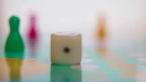 Shallow focus on falling dice in front of game pawns on board Stock Footage 312525828