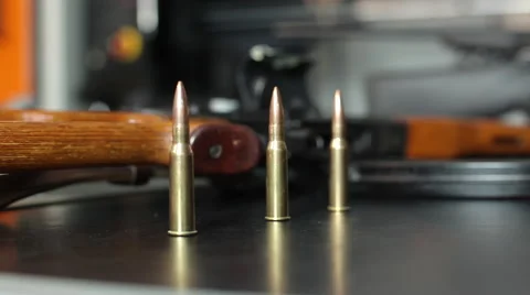 Shallow focus hero shot of three rounds of ammo in front of a soft focus rifle. Stock Footage 64093517