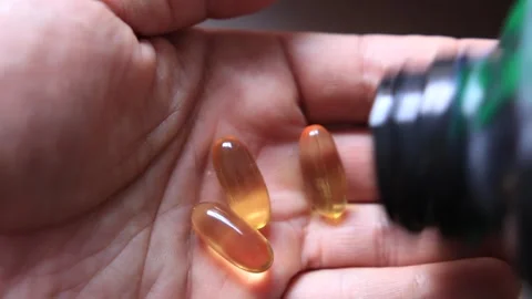 Shallow focus shot from a man counting omega 3 capsules  on his hands Stock Footage 279463220
