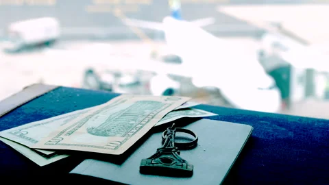 Shallow focus view on currency keychain and passport atop travel case at airport Stock Footage 315652144