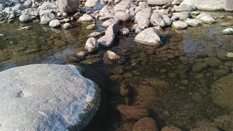 Shallow river flowing over exposed stones during dry season 스톡 동영상 345569375