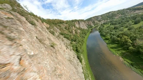 A shallow river flows near the sole of the mountain. Light clouds move across Stock Footage 156463778