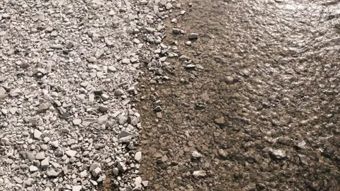 Shallow river water flowing along a rocky shoreline seen from above. Clear Stock Footage 325739164