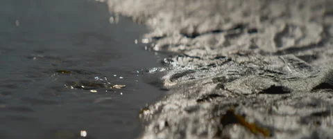 Shallow sea waves lapping against organic sand patterns at shore Video stock 337792940
