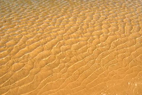Shallow surf with sand of a beach with patterns Stock Photos