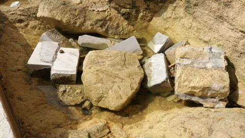 Shallow tide pool collects among weathered stone rubble close texture detail Stock Footage 341800993