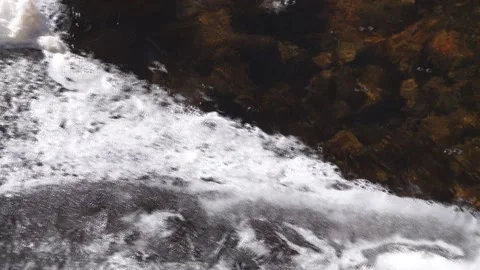 A shallow transparent river. Melting ice on the river. Foam on the water Stock Footage 172000145