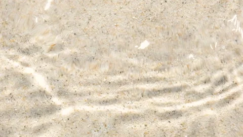 Shallow water flows over sandy bottom with ripples and sun reflections. Natural Stock Footage 312124430
