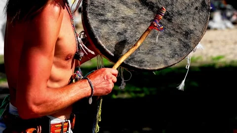 Shaman playing a round leather frame drum in the summer nature Stock Footage 331654011