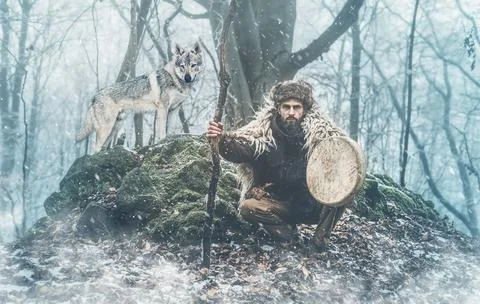 Shamanic man playing on shaman frame drum in the nature. Stock Photos