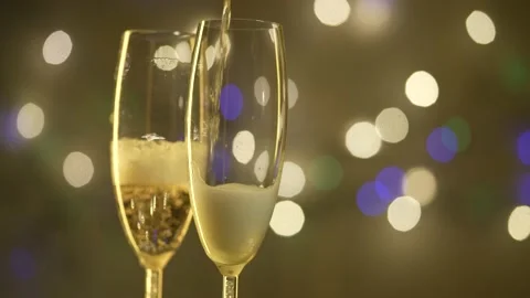 Сhampagne is poured into glasses, Christmas background. Slow motion. Stock Footage 231795053