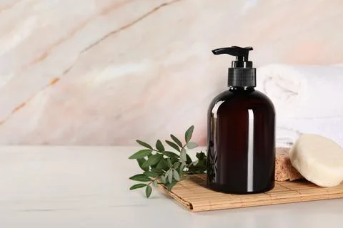 Shampoo bottle, solid shampoo bars and folded towels on white marble table,.. Stockfoto's