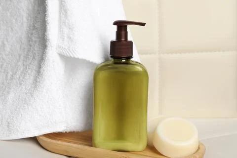 Shampoo bottle, towel and solid shampoo bar on white table 스톡 사진