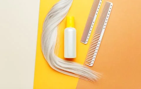 Shampoo orange bottle with lock curl of blonde hair and combs. Hairdresser to Stock Photos