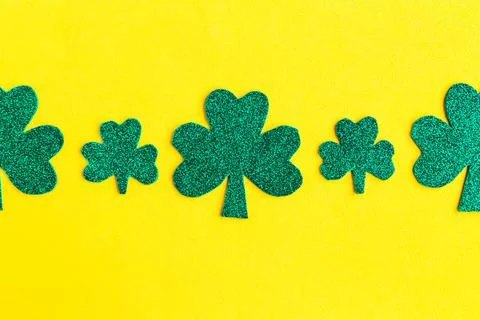 Shamrocks pattern on bright yellow background. Minimal concept. Copy space fo Stock Photos