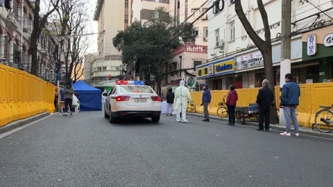 SHANGHAI, CHINA - APRIL 4, 2022: Police car drives past covid test line Stock Footage 174556864