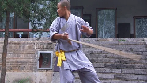 Shaolin monk practicing stick fighting Stockbeeldmateriaal 89813173