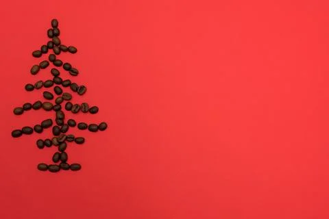 The shape of a Christmas tree made of coffee beans on a red background. The Stock Photos
