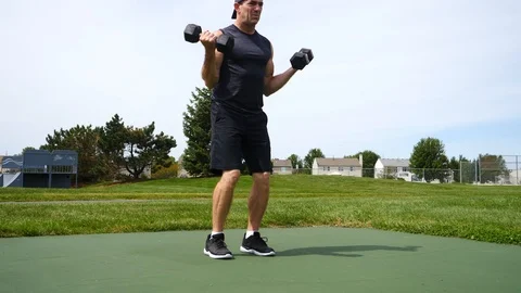 In shape man doing biceps curls at park on sunny day, 4k, 60fps. Stock Footage 115272262