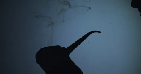 The shape of a  man hand lighting a pipe on blue background Stock Footage 123504244