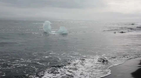 Shaped peace of ice floating in the waves near the black sand beach, Iceland Stock Footage 33778550