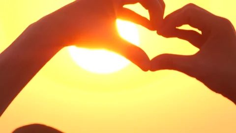Shaping heart with hands over the sunset sunrise by the ocean or sea. High Stock Footage 137806359