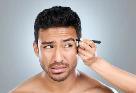 Shaping your brows isnt exactly painless. a handsome man getting his eyebrows Stock Photos