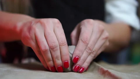Shapping a piece of gray pottery clay on a table with cloth by female hands Stock Footage 257259890