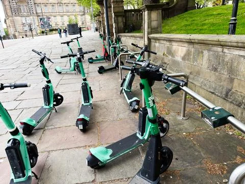 Shared  Bolt electric scooters parked on a stone sidewalk beside historic b.. Stock Photos