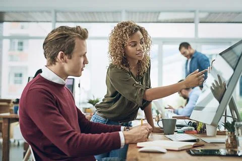 Shared resources bring shared success. two young colleagues using a computer Stock Photos