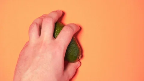 Sharing avocados on a peach background, close-up. Avocados in a woman's and men Video stock 126602167
