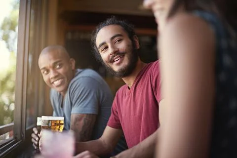 Sharing drinks and laughs. a group of friends enjoying themselves in the pub. Stock Photos
