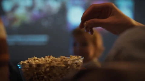 Sharing popcorn while watching a movie at a cozy theater with friends Stock Footage 301407800